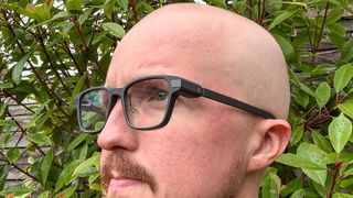 Even Realities G1 Smart Glasses being worn by person with bush and fence in background