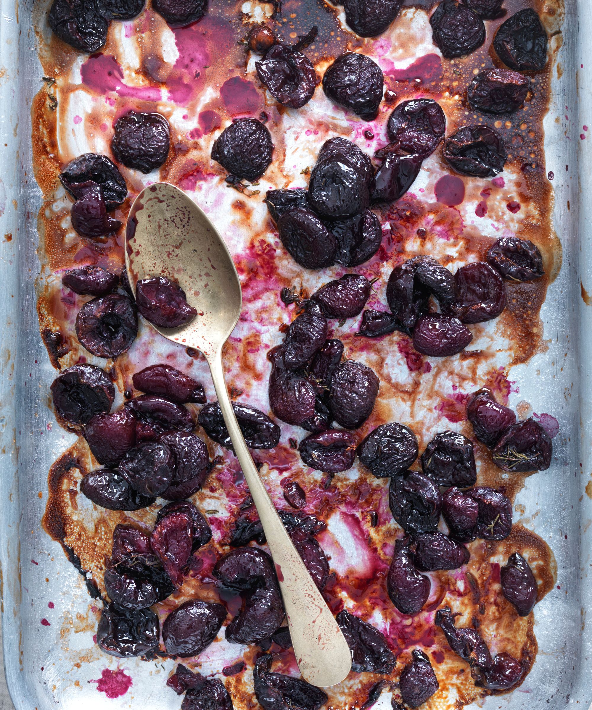 Baking tray of roasted cherries with a spoon in