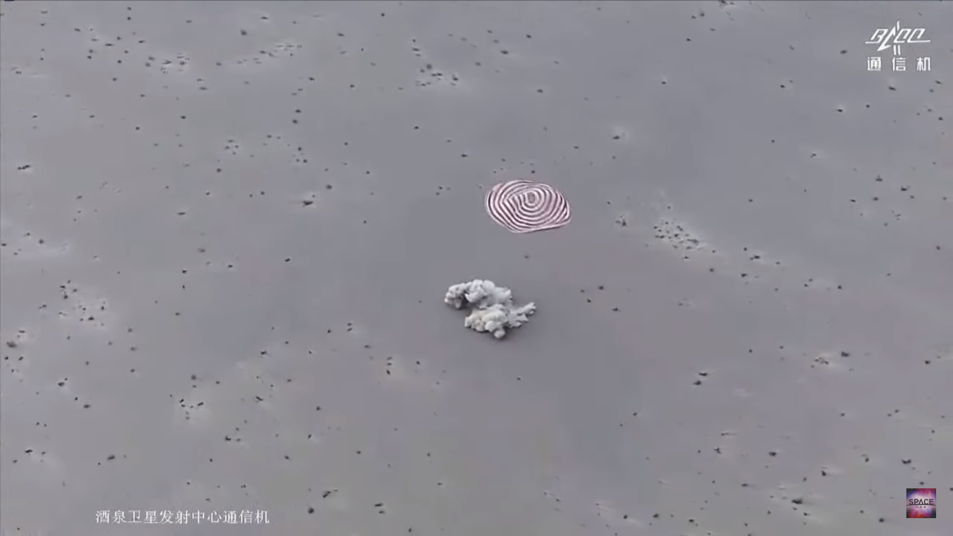 Chinese space capsule kicking up a dust cloud while landing as its parachute drifts to Earth.