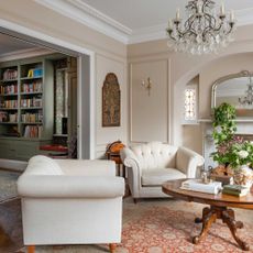 view of elegant living room in Edwardian home with antiques and chandelier leading into green painted library