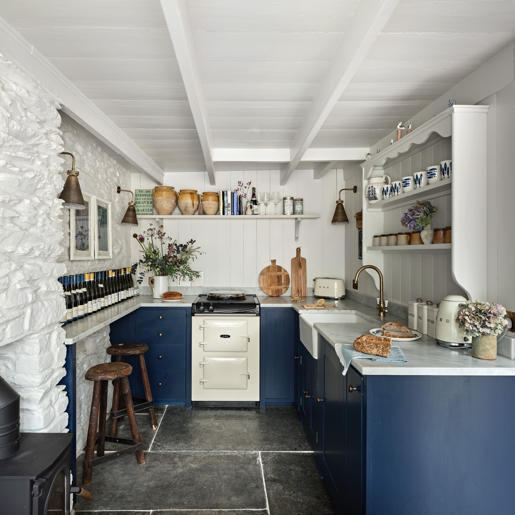 A white-painted kitchen with panelled walls and ceiling and dark blue cabinets