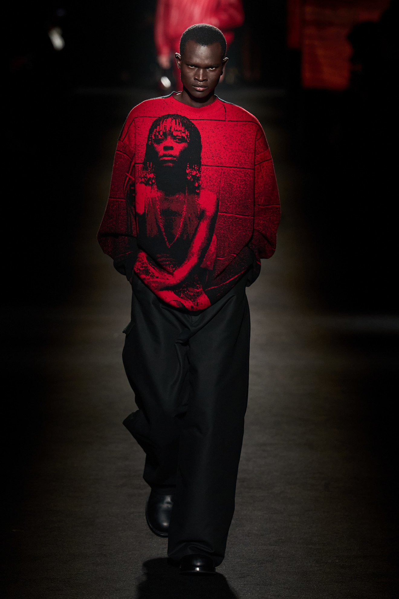 A model walking in the Balenciaga F/W 26 show during Paris Fashion Week wearing a red sweater with Euphoria actress Danielle Deadwyler printed on it.