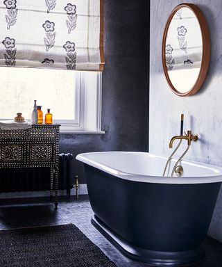 A black bathroom with a decorative storage cabinet under the window and block printed blinds