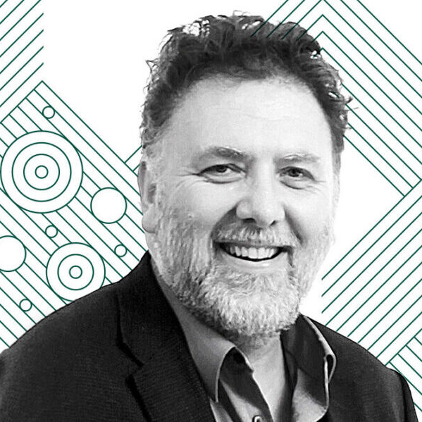 male with short curly hair and beard wearing suit jacket and shirt