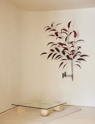 Red foliage lamp on the wall and stone and glass coffee table on cream floor