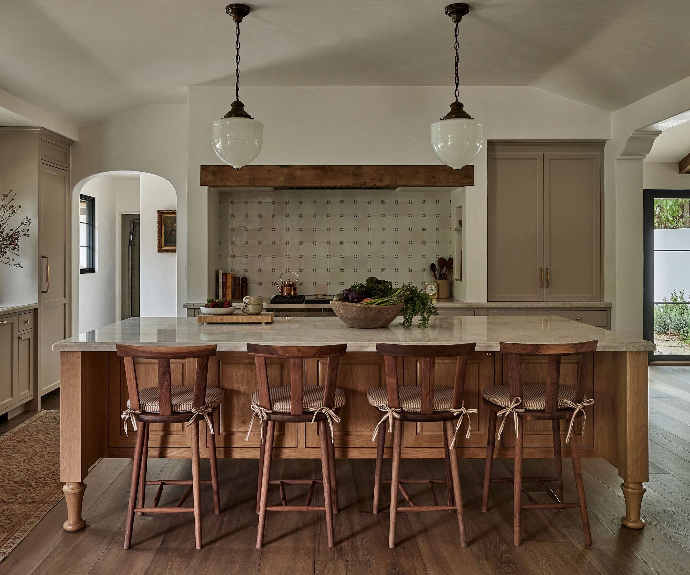 A neutral kitchen with a wooden island and a Delft tile backsplash