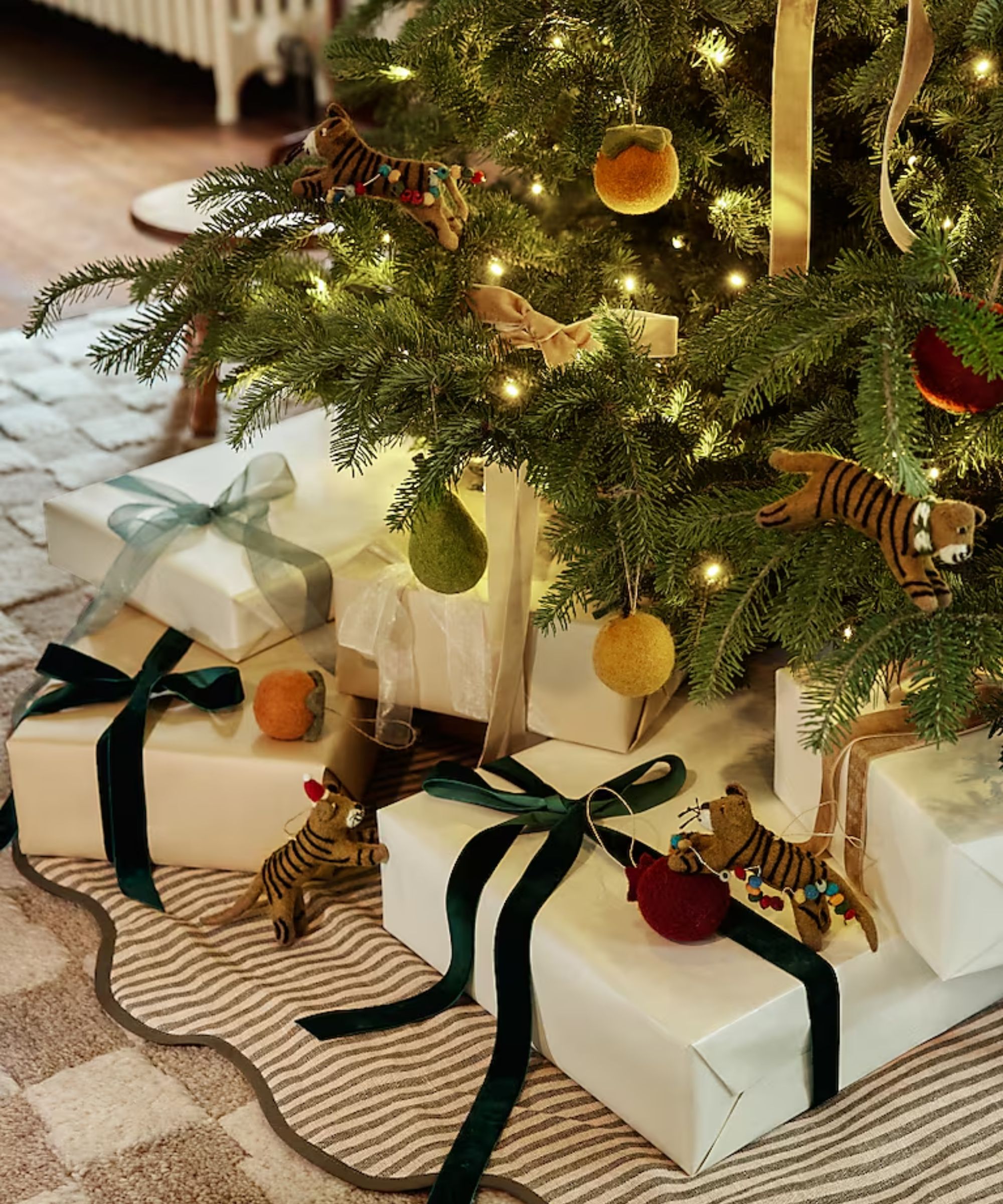striped wavy Christmas tree skirt on a checkboard rug with a large lit tree decorated with bows and felt ornaments