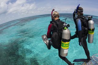 Two male scuba divers prepare to fall into the water in the Florida Keys