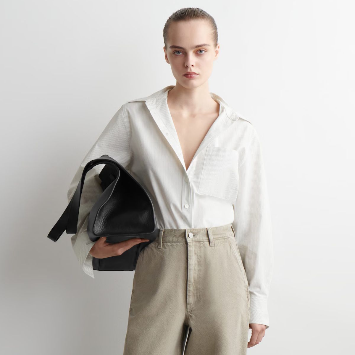 Woman wears white shirt, grey jeans and carries black bag