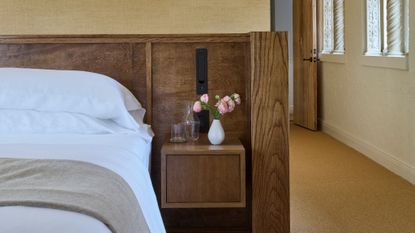 close-up of bed with white sheets and wooden headboard with floating bedside table