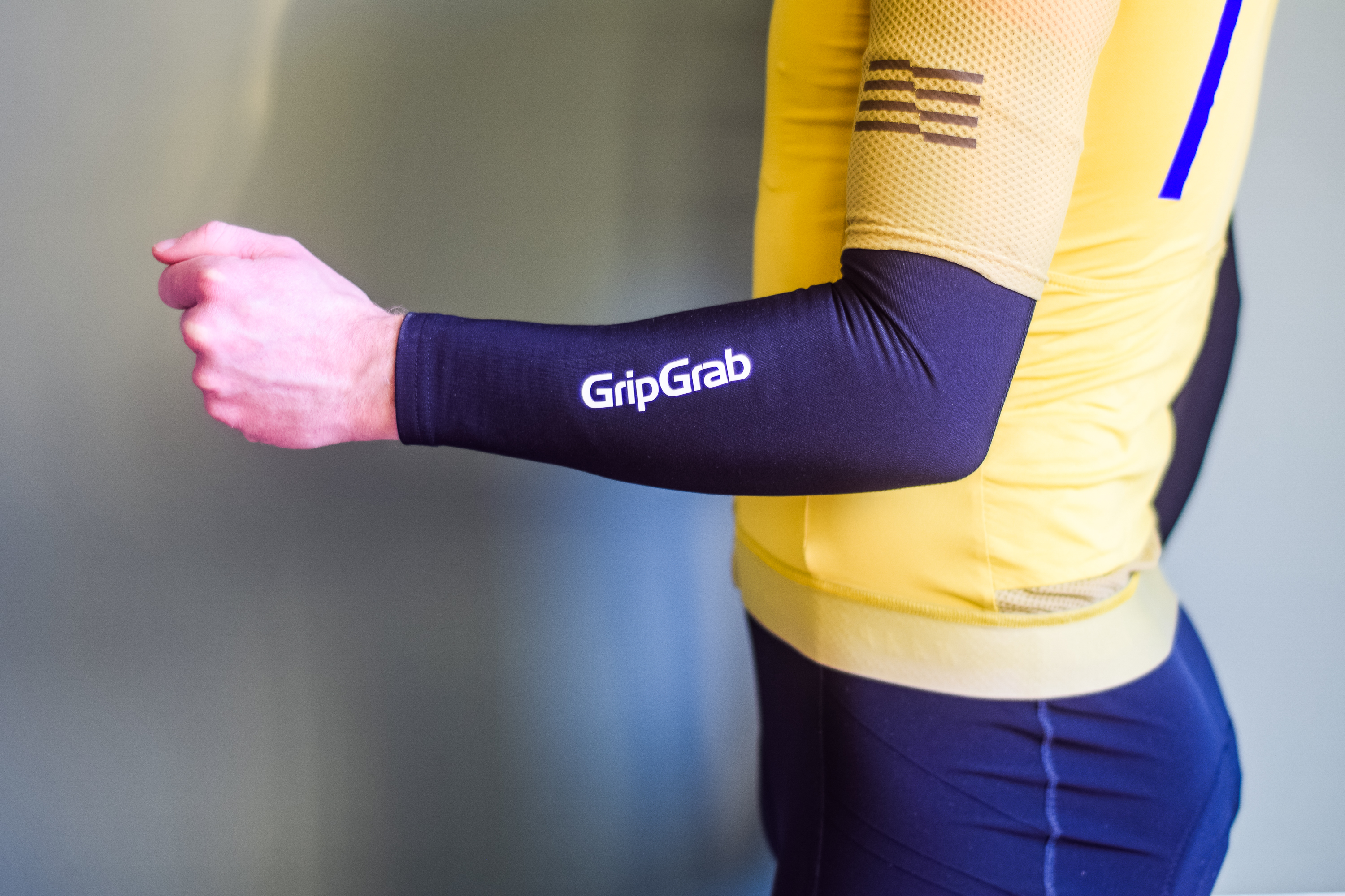 A man in a yellow cycling jersey wearing black arm warmers