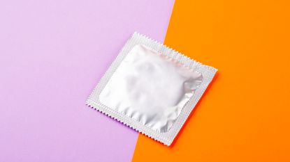 condom in packaging with a colored pink and orange background