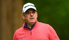 McGinley watches his tee shot in a red jumper