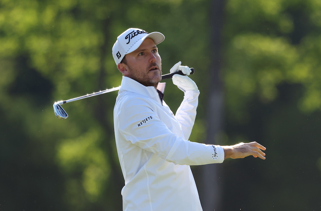 Russell Henley takes a hand off the club in his follow through on an iron shot