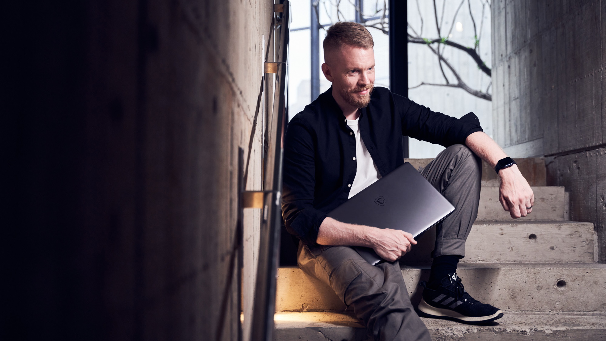 Man sitting on steps holding a laptop