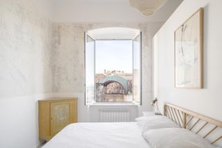 House by the Bailucchi by llabb features a bedroom with a double bed, white linen, and a window overlooking a courtyard.