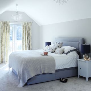 master bedroom with blue bed and white walls