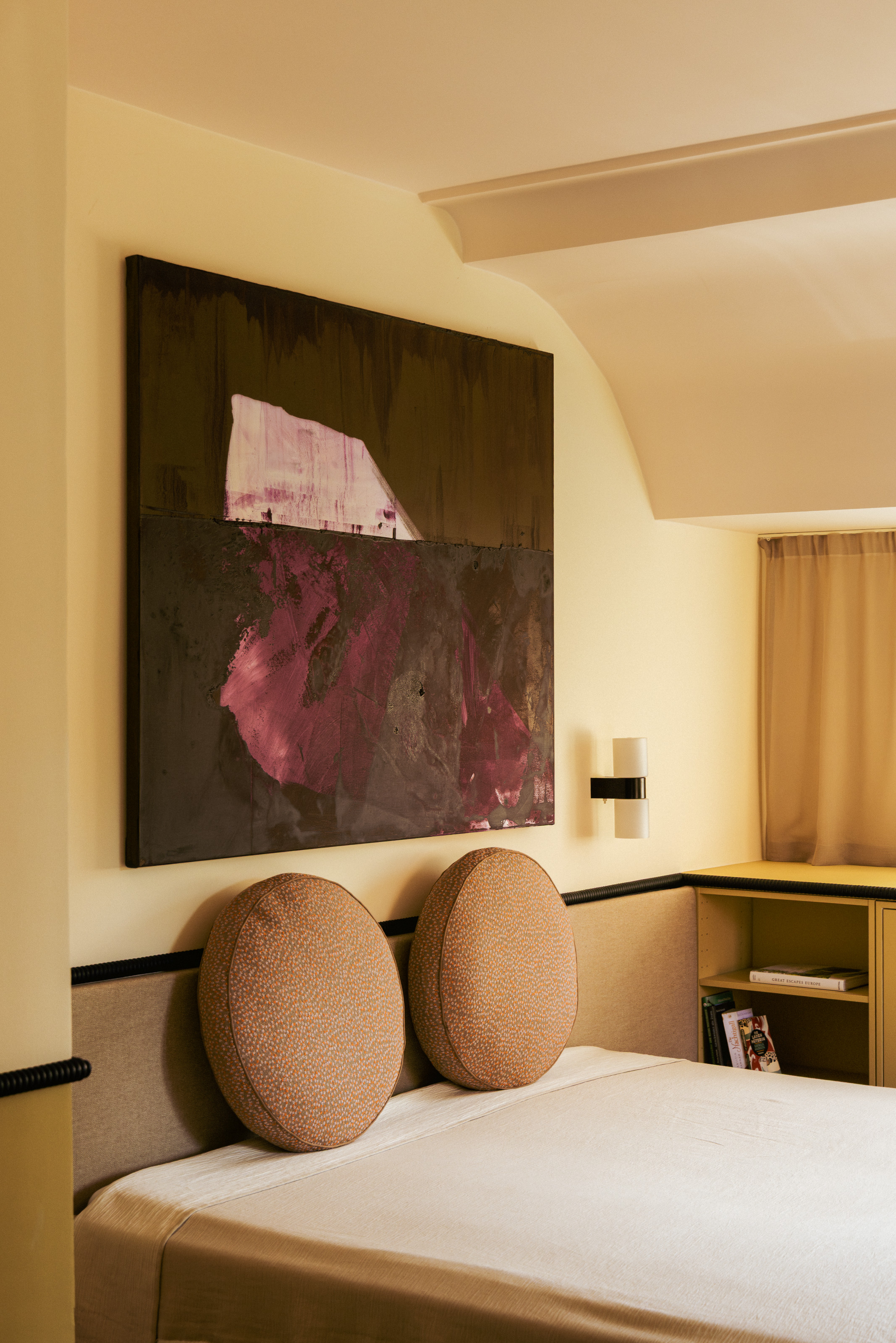 Yellow bedroom with built-in brown upholstered headboard, brown round throw pillows and yellow built-in desk