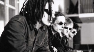 A portrait of Swervedriver in 1998. The band are sat down and all wearing sunglasses