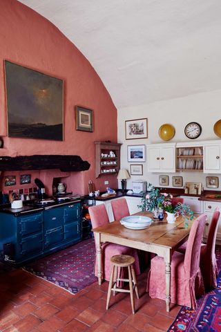 pink painted kitchen diner with blue aga in a cottage