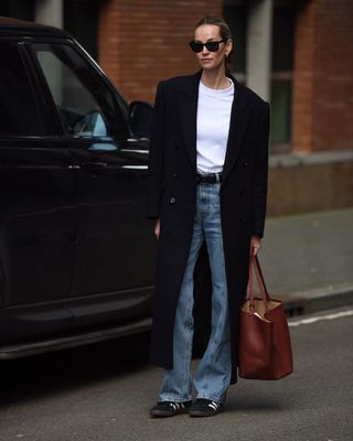 woman wearing flare jeans and black long coat