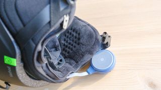 Close-up of a ski helmet ear pad with an OutdoorMaster speaker sticking out of its zippered compartment