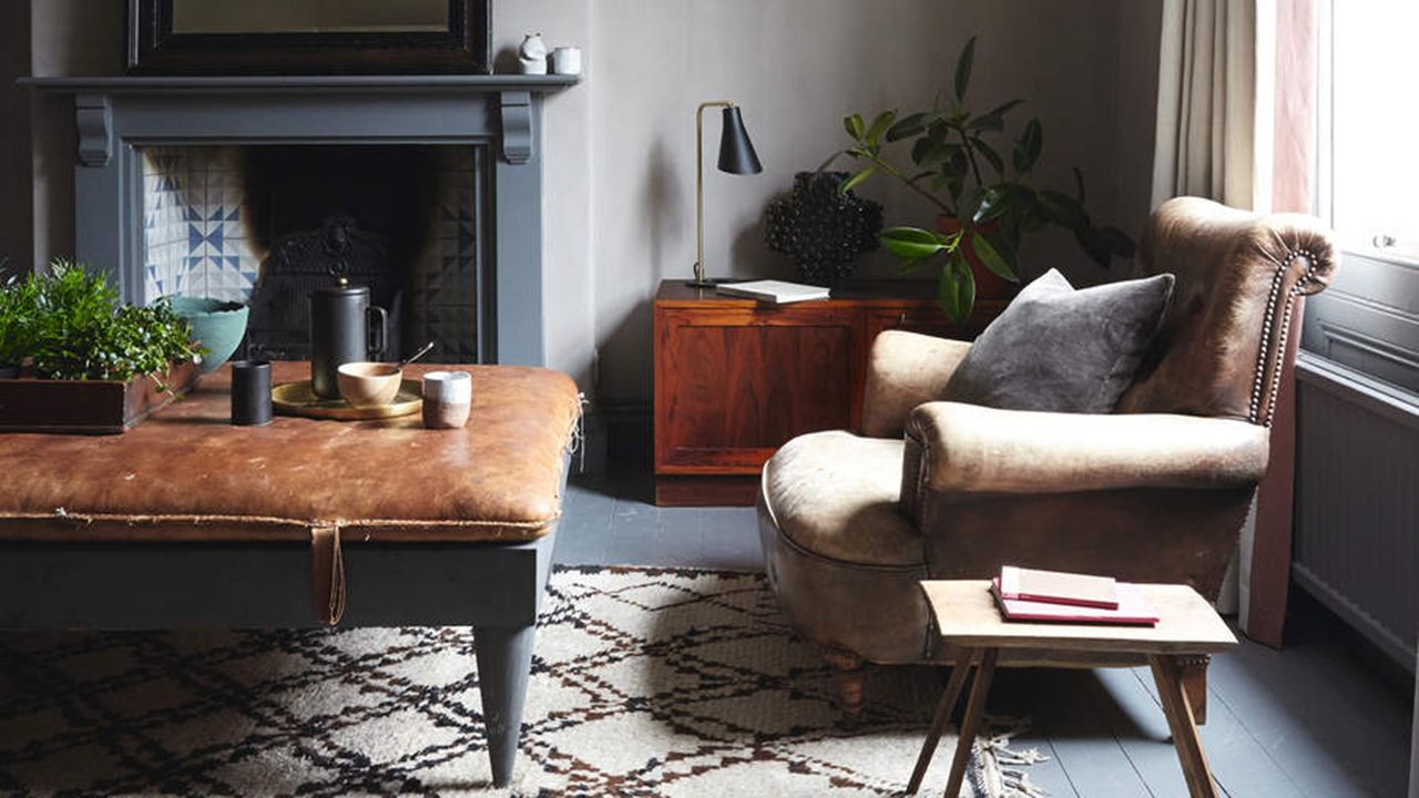 Living room with painted floorboards, fireplace and mirror and sofa in a former Victorian mill, a renovated period house in Yorkshire, home of Lee Thornley.