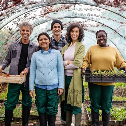 Group of people stand in greenhouse with baskets of produce