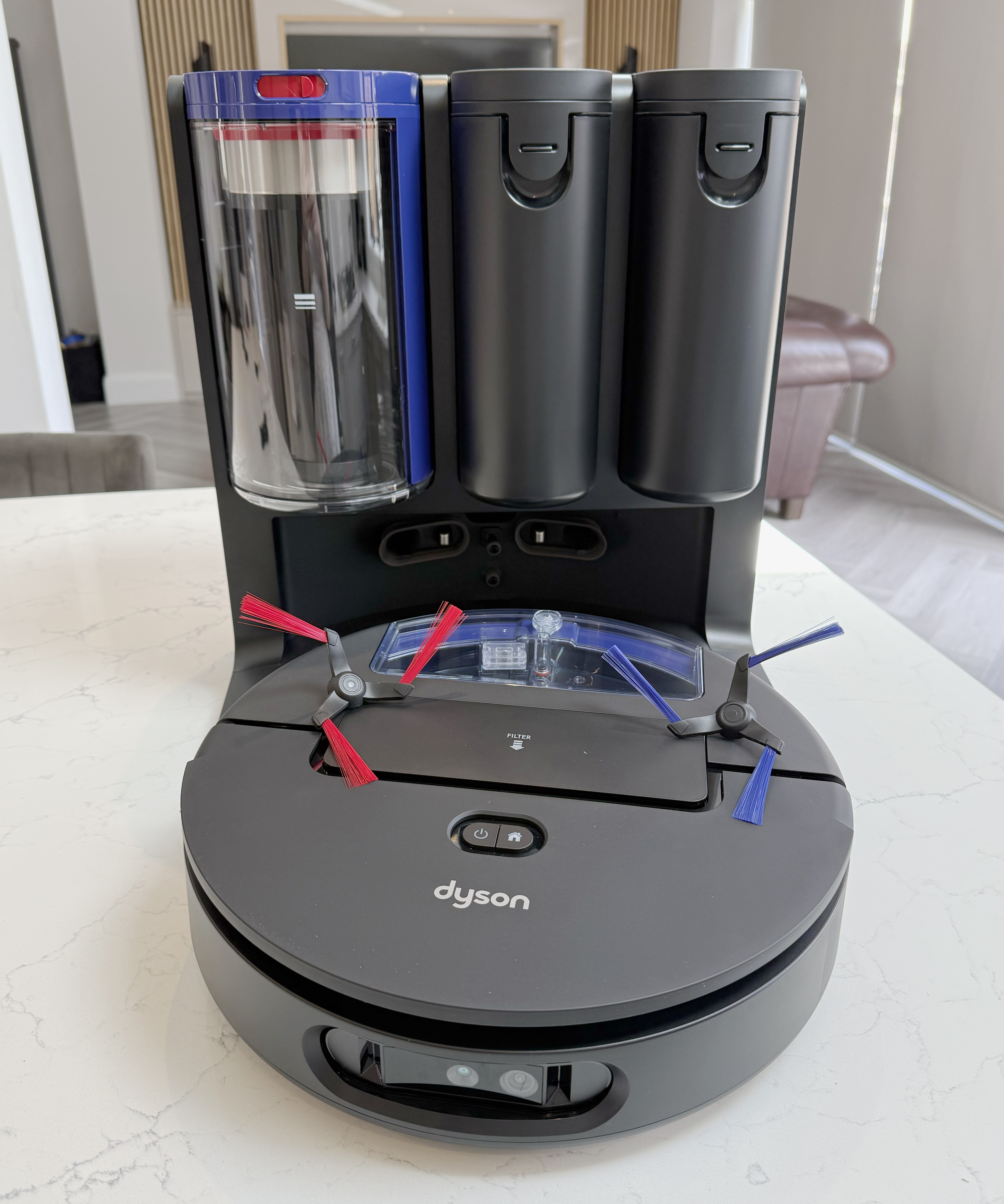Dyson Spot+Scrub Ai robot sitting on its dock with red and blue side brushes visible