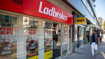 A man walks past a branch of Ladbrokes