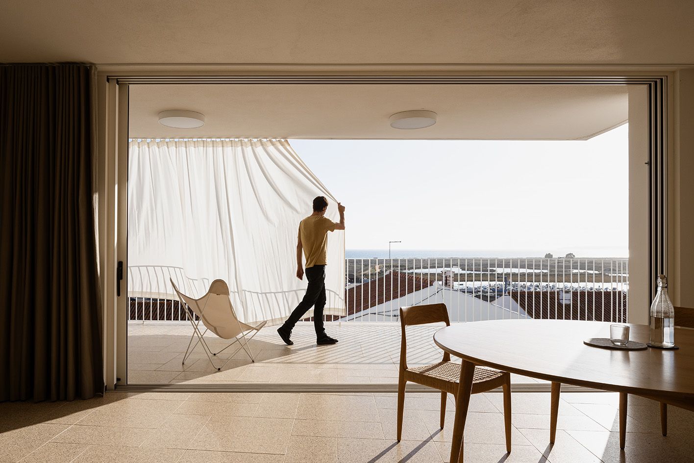 man drawing curtain to terrace on sunny day at Casa M