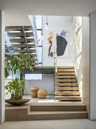 A wood staircase leading to an upper floor with a houseplant and wooden decor