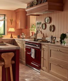 A pink kitchen with wood kitchen cabinets and marble countertops