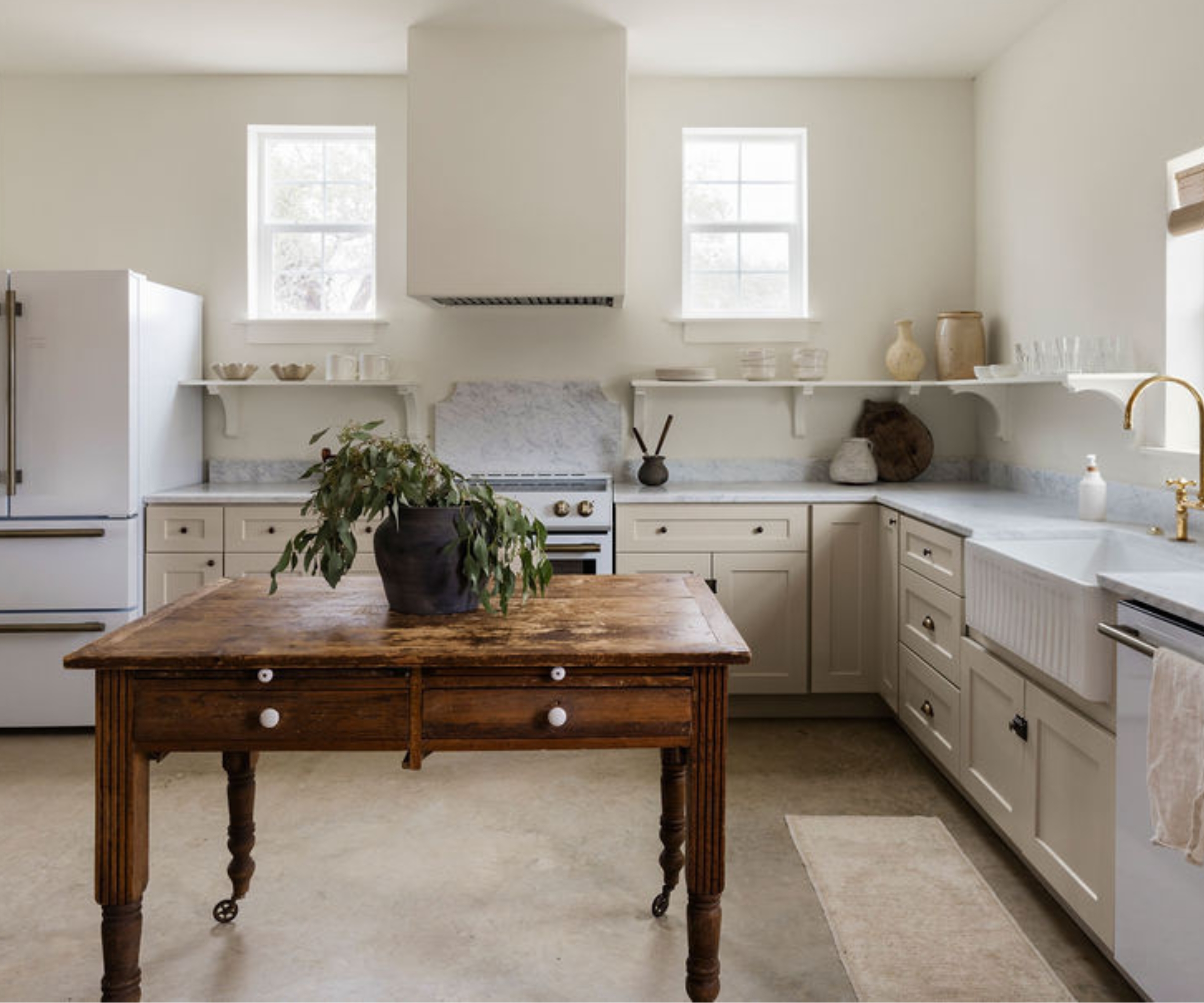 an L-shaped kitchen with marble countertops, Alabaster by Sherwin-Williams on the walls and cabinets, and a wood freestanding island