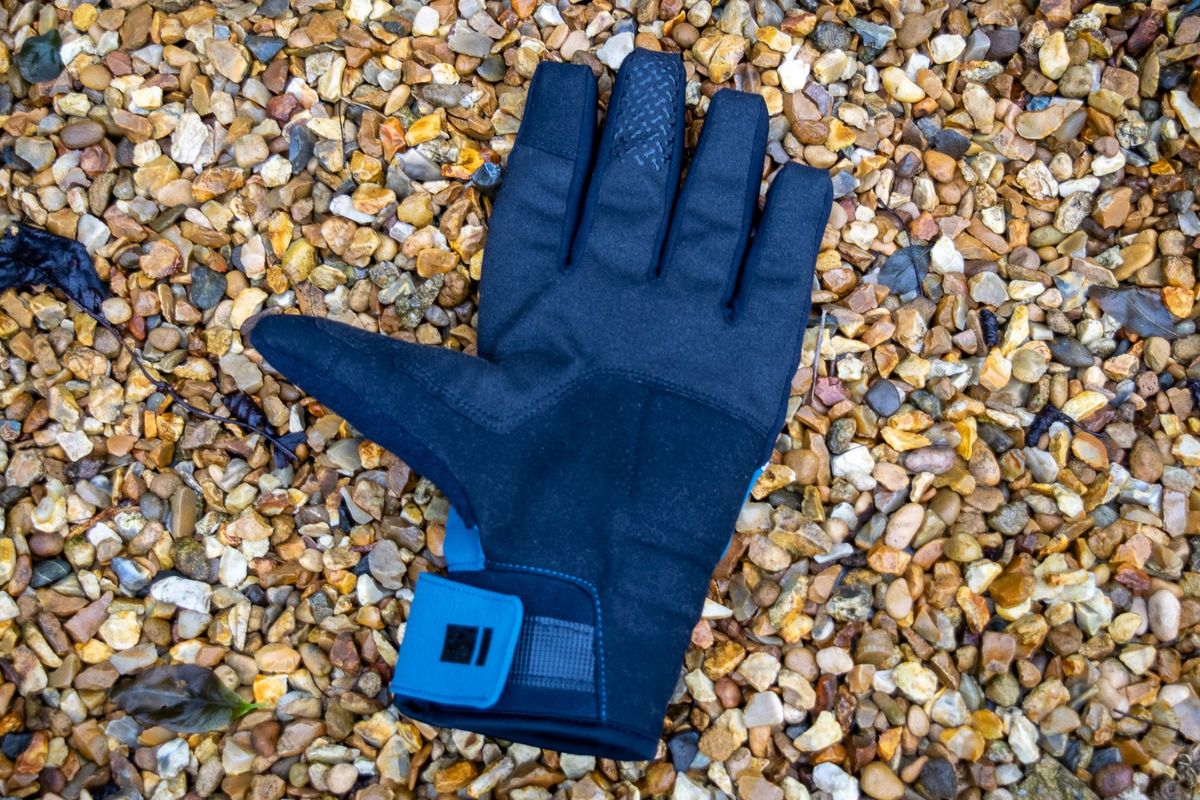 A pair of blue Madison DTE waterproof gloves on gravel