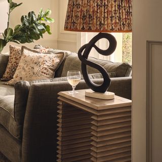Sculptural side table with table lamp in living room next to sofa