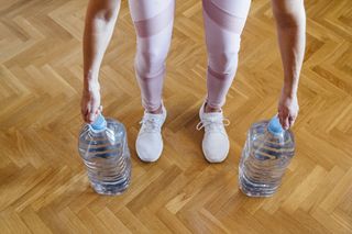Strength training for women: a woman uses water bottles for a home workout