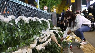A woman lays flowers as she mourns at the street of a deadly stampede during a Halloween festival in Seoul