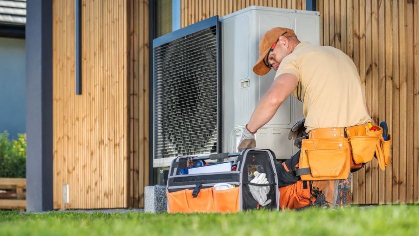 HVAC worker working on a modern heat pump outside a house