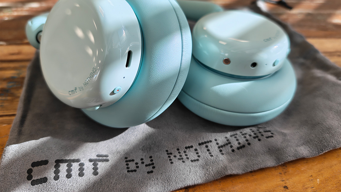 CMF Headphone Pro; a pair of light green headphones on a wooden table