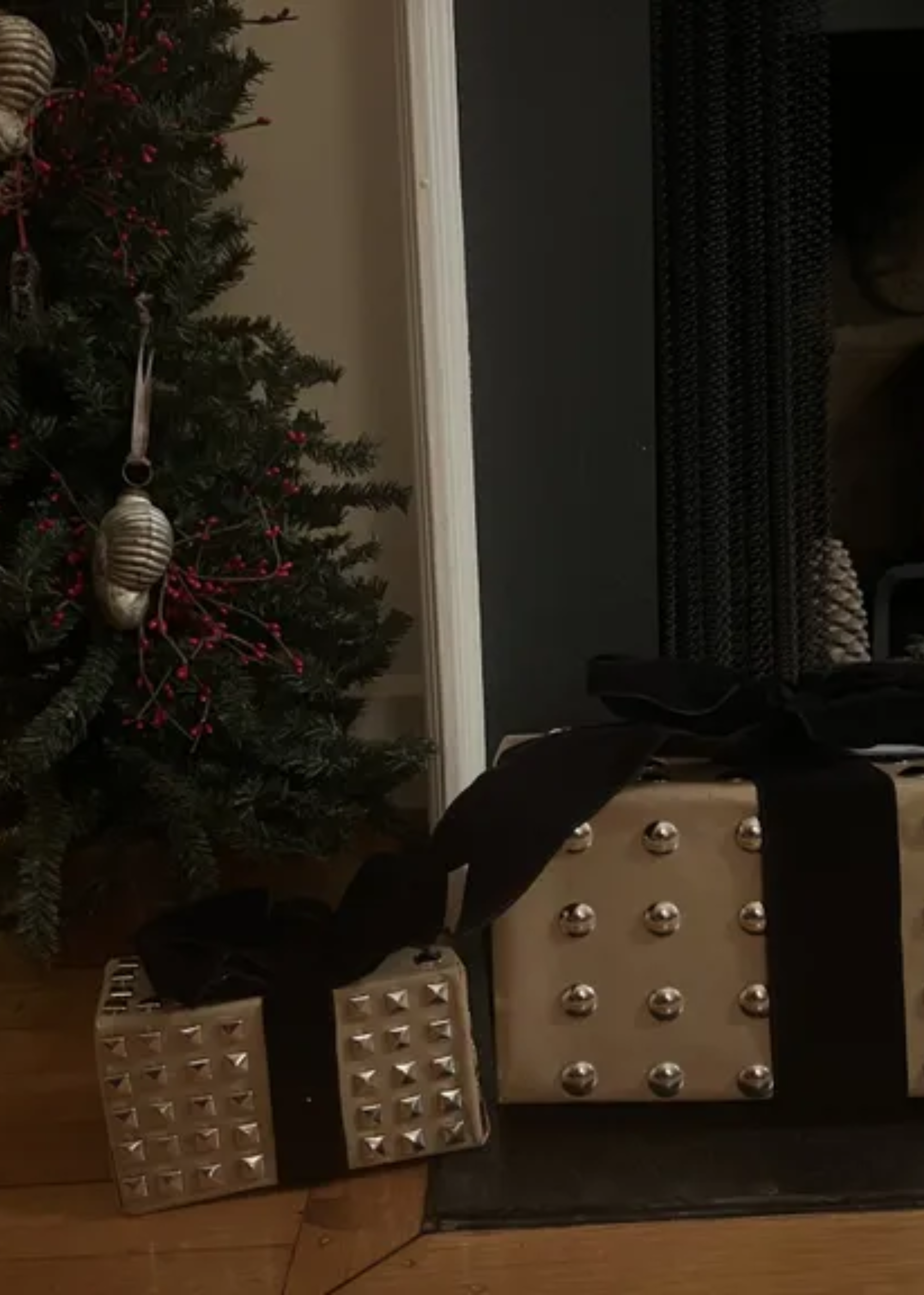 A pair of studded Christmas presents by a tree and fireplace