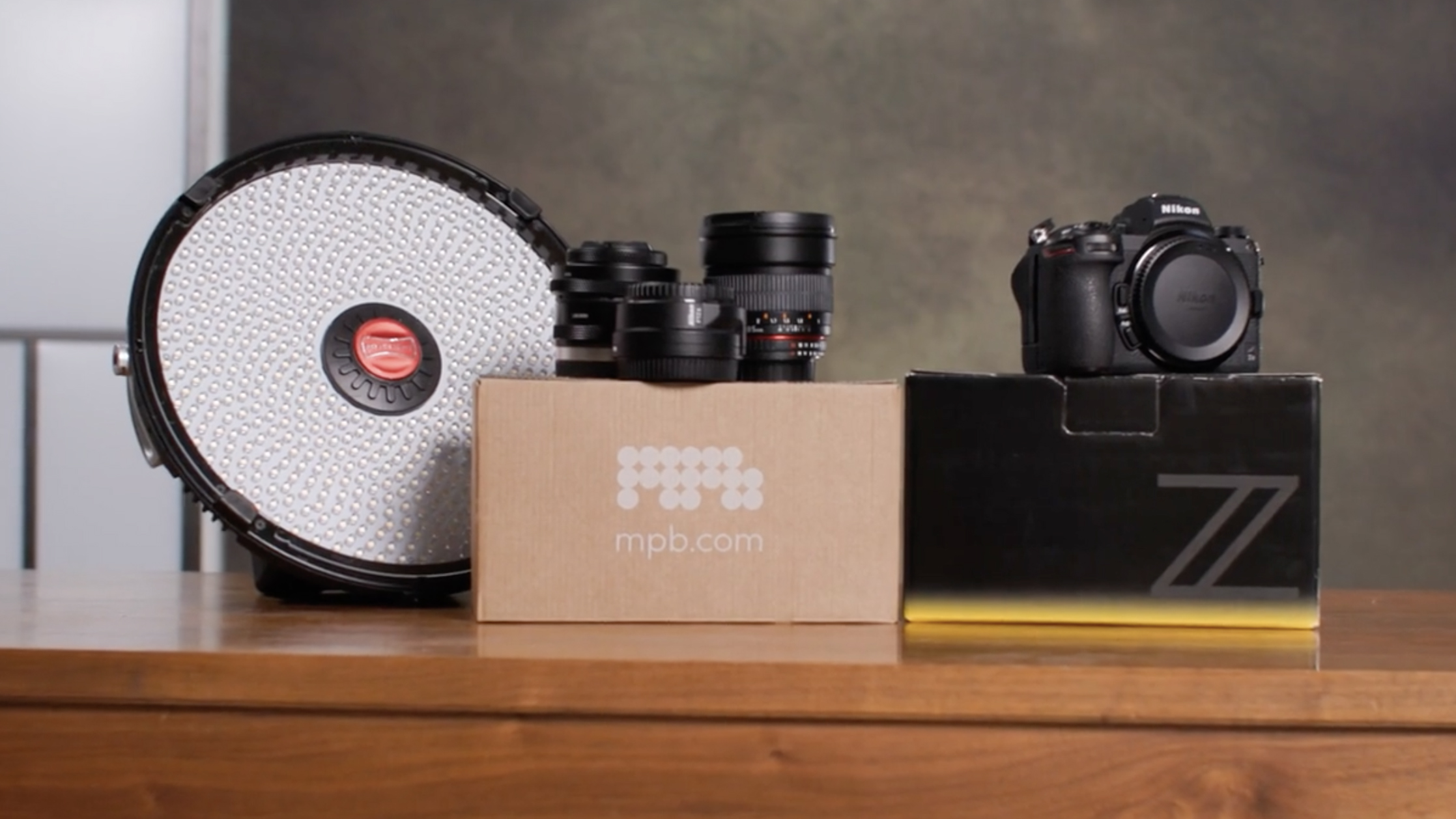 Second-hand camera and equipment, with packaging from retailer MPB, on a wooden surface