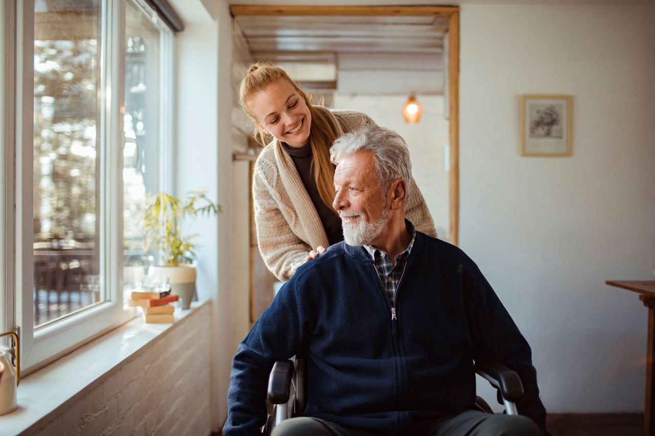 A woman pushes a man sitting in a wheelchair.