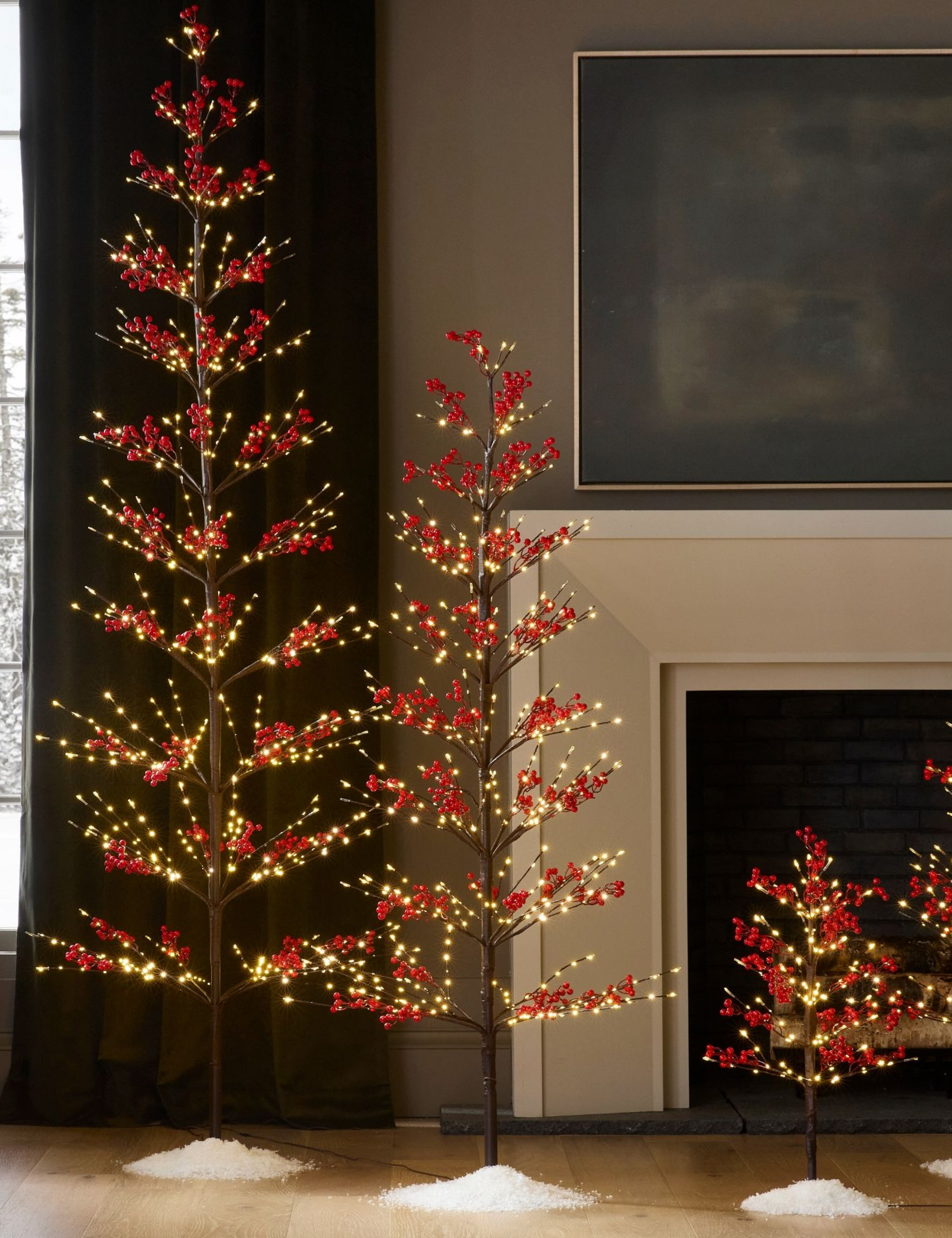 Twinkling twig trees with red berries clustered in a cozy living room
