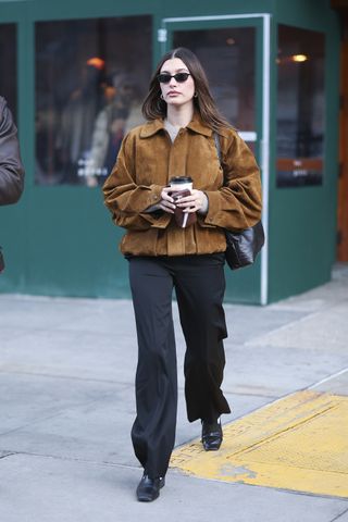 Hailey Bieber seen in SoHo on January 30, 2025 in New York City wearing a brown suede jacket and the row bag