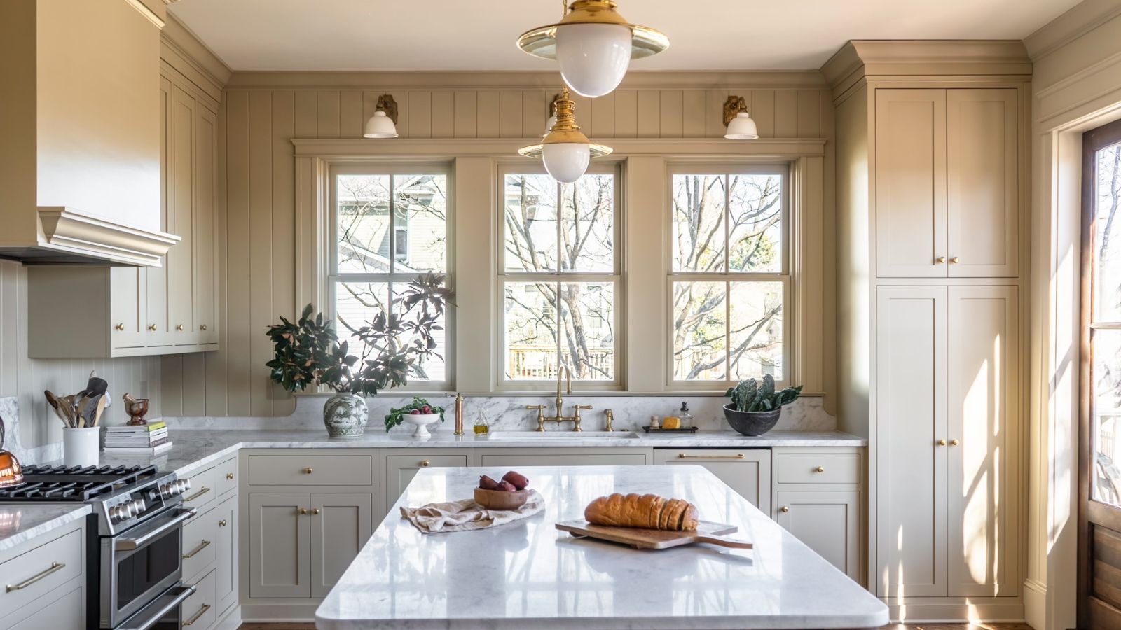A large L-shaped kitchen with an island, wall paneling, and a sink beneath the window