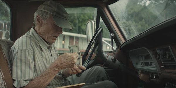 Earl Stone looking at a stack of money in The Mule