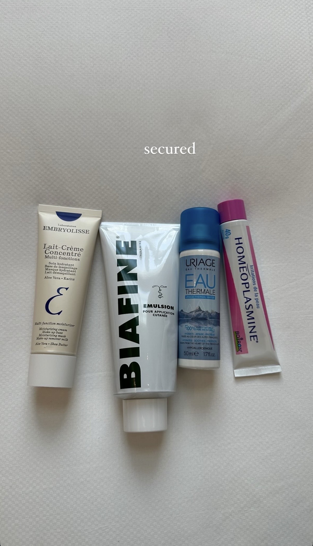 Photo of four French pharmacy skincare products on a bed