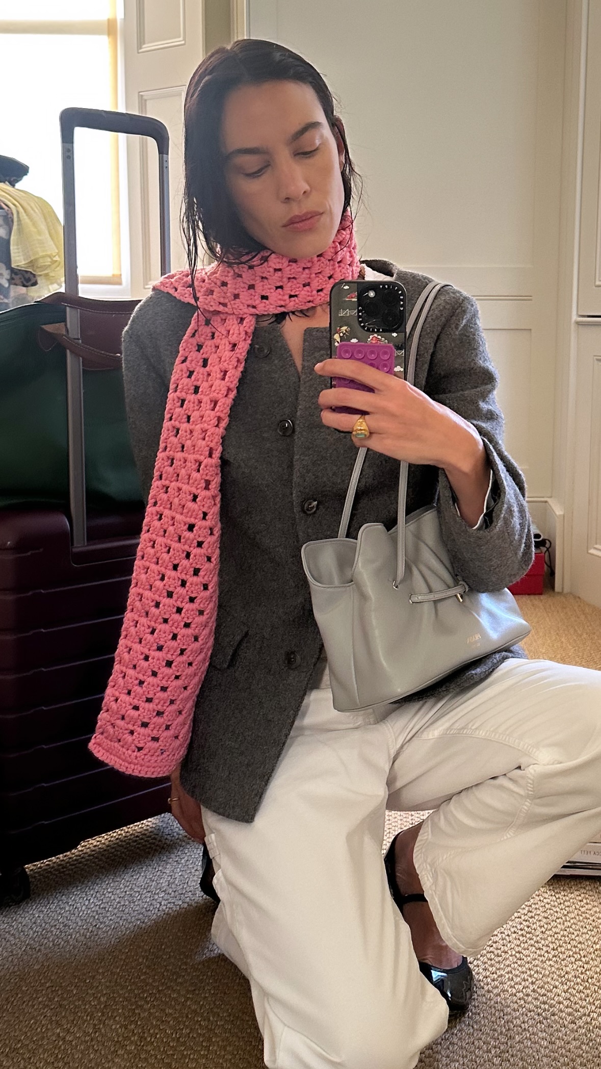 Alexa Chung takes a mirror selfie wearing the Prada Dada bag in grey with a grey blazer and white jeans.