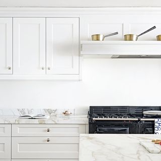 White kitchen with mable worktops and extractor hood that doubles as a shelf